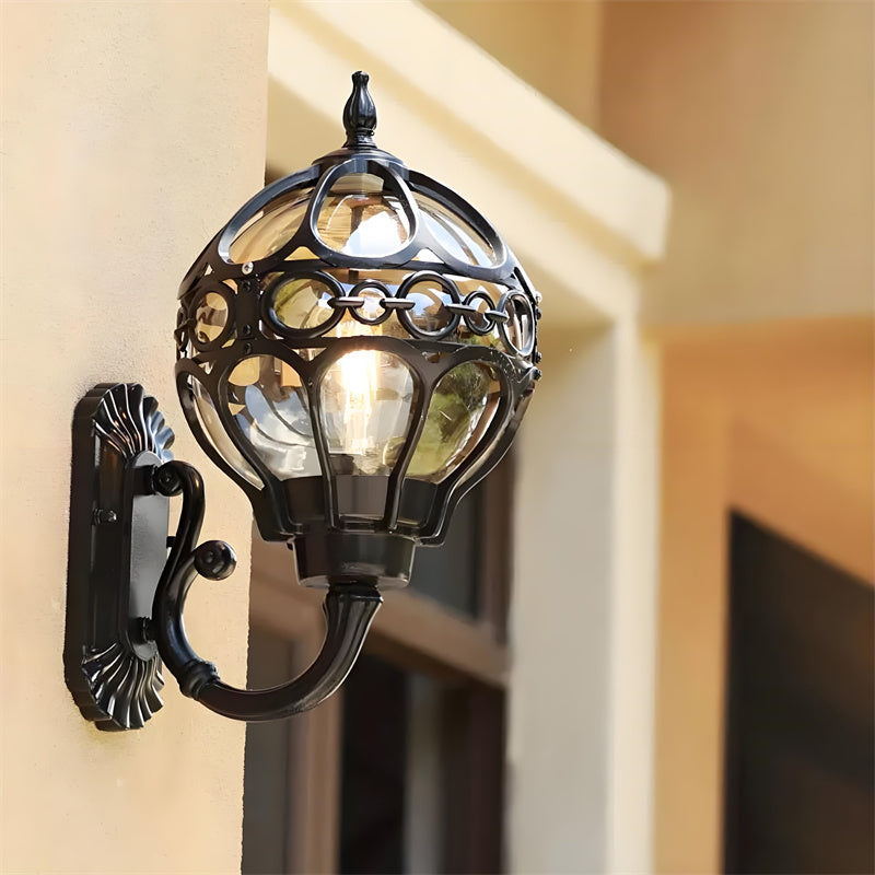 "Elegant bronze/black outdoor wall light with matte finish, transparent globe shade, perfect for garden or porch lighting."