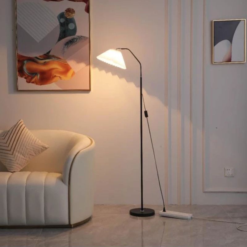 Elegant floor lamp with a pleated fabric shade in a room, providing soft ambient lighting and a classic, versatile design.