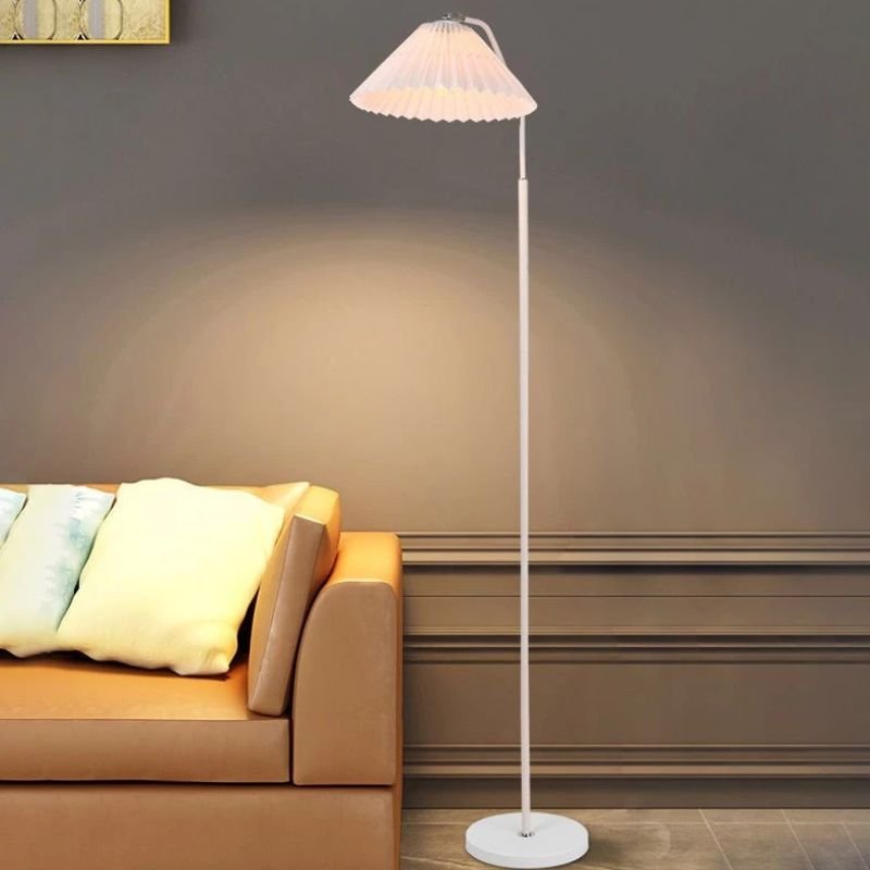 Elegant floor lamp with a pleated fabric shade in a room, providing soft ambient lighting and a classic, versatile design.