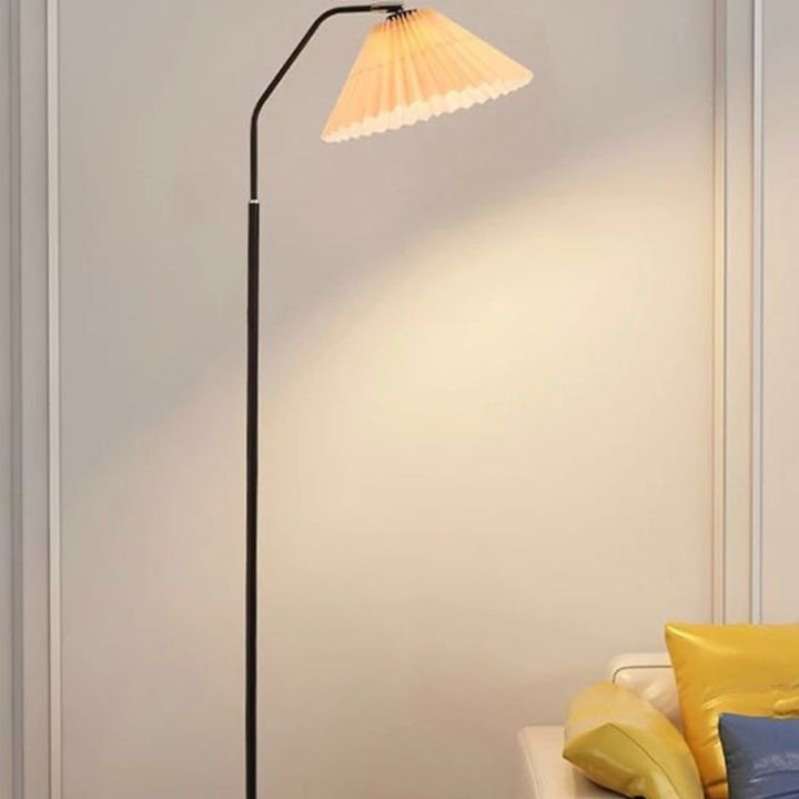 Elegant floor lamp with a pleated fabric shade in a room, providing soft ambient lighting and a classic, versatile design.