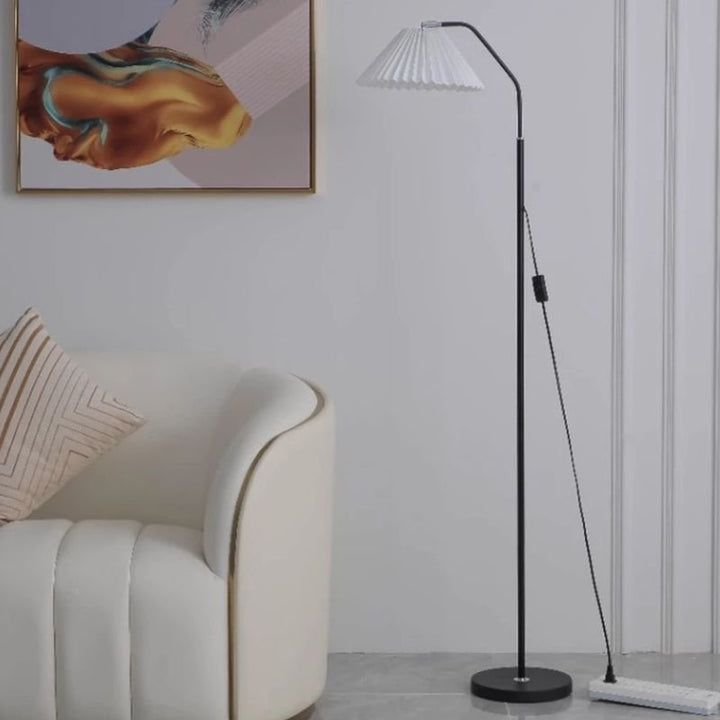 Elegant floor lamp with a pleated fabric shade in a room, providing soft ambient lighting and a classic, versatile design.