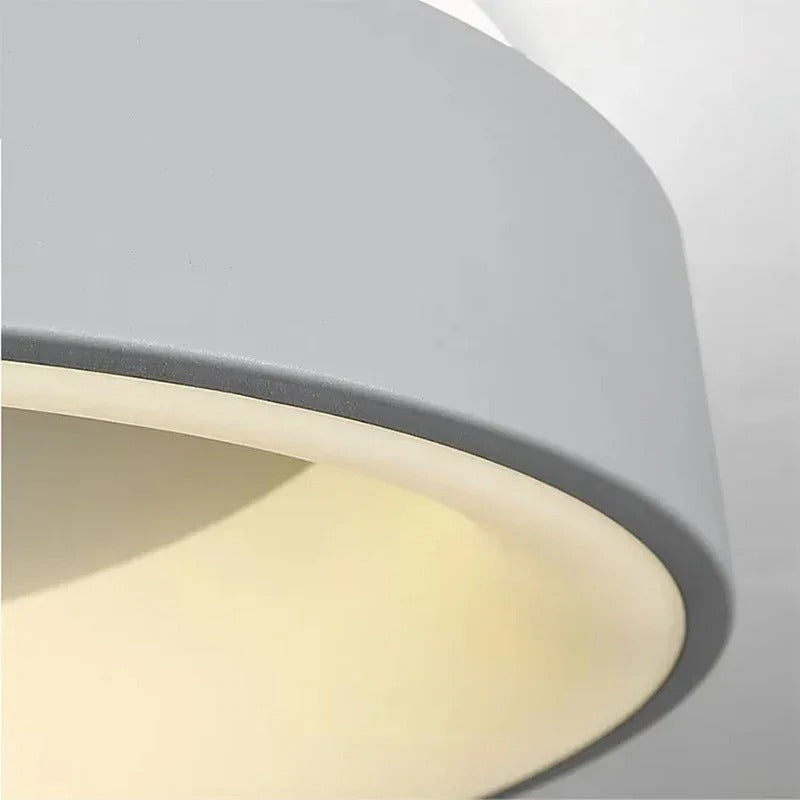 Modern circular LED ceiling light with sleek metal frame, soft ambient lighting; available in grey, white, wood finishes.