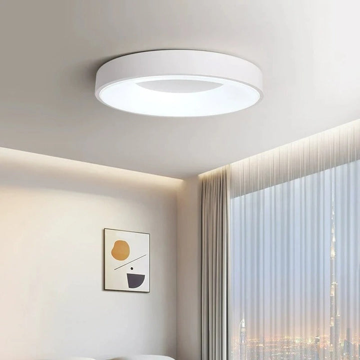 Modern circular LED ceiling light with sleek metal frame, soft ambient lighting; available in grey, white, wood finishes.