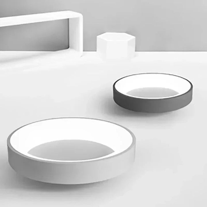 Modern circular LED ceiling light with sleek metal frame, soft ambient lighting; available in grey, white, wood finishes.
