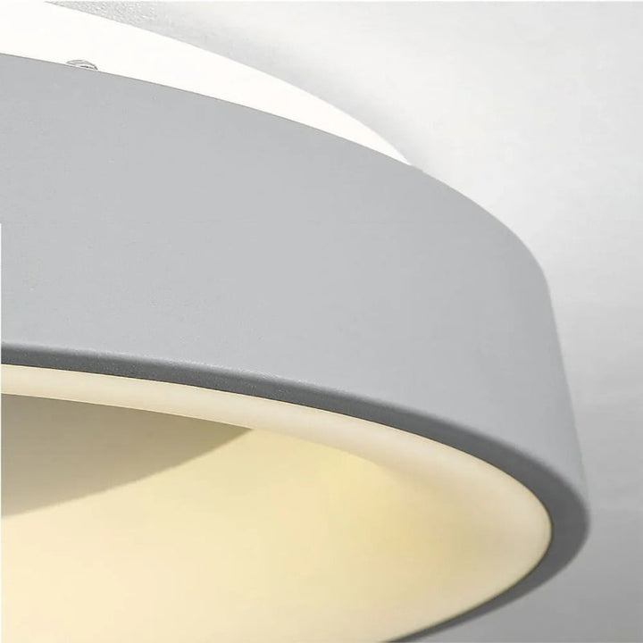 Modern circular LED ceiling light with sleek metal frame, soft ambient lighting; available in grey, white, wood finishes.
