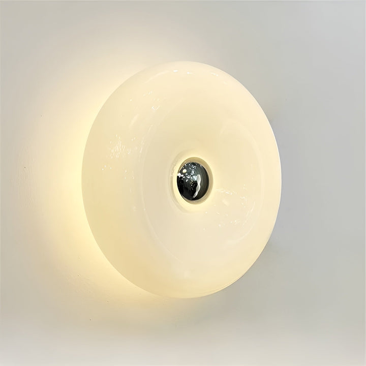 Orange donut-shaped LED lamp for table or wall, made of glass and metal, offering warm glow and whimsical décor touch.