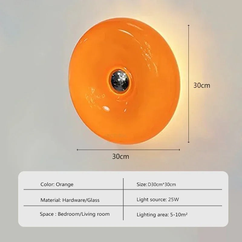 Orange donut-shaped LED lamp for table or wall, made of glass and metal, offering warm glow and whimsical décor touch.