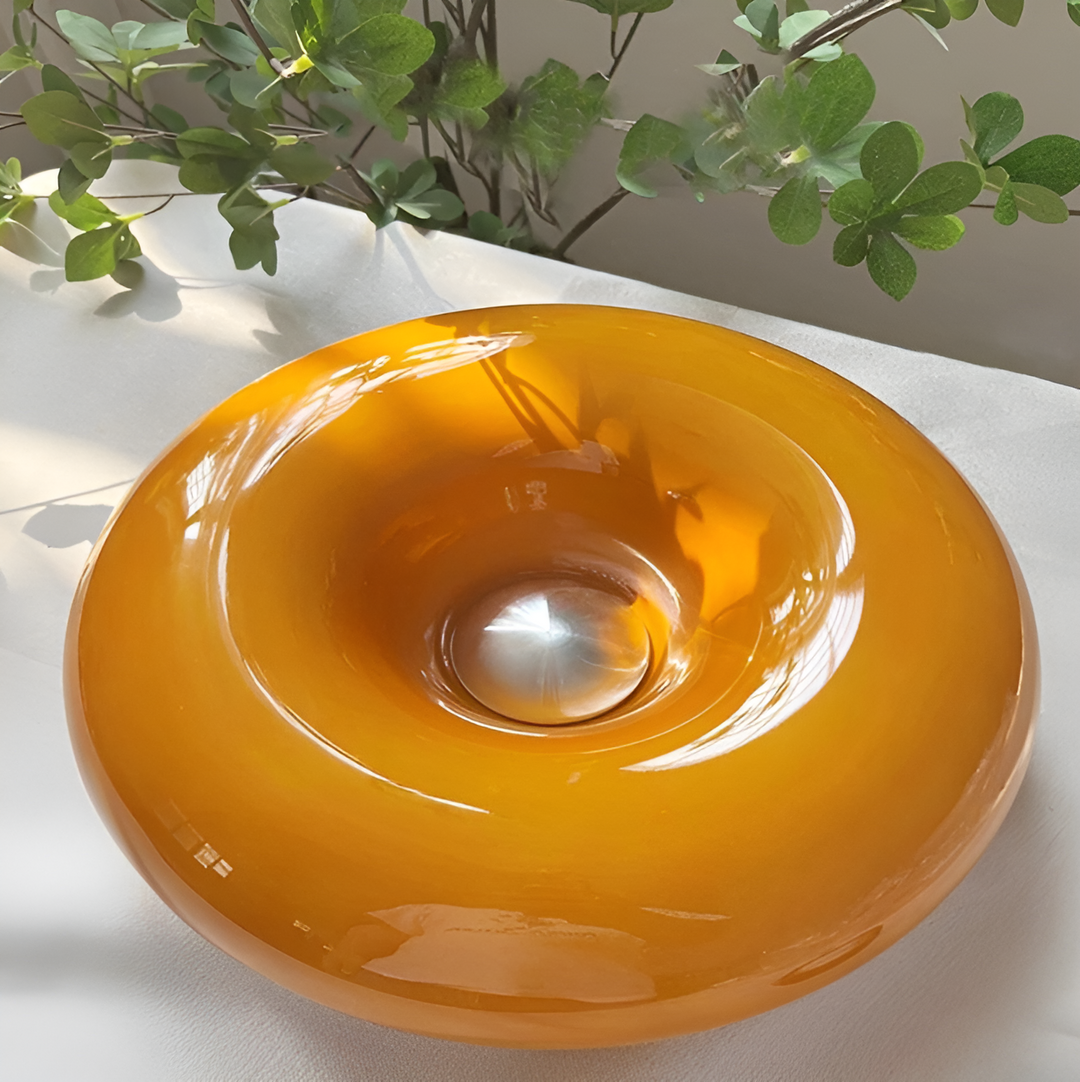 Orange donut-shaped LED lamp for table or wall, made of glass and metal, offering warm glow and whimsical décor touch.