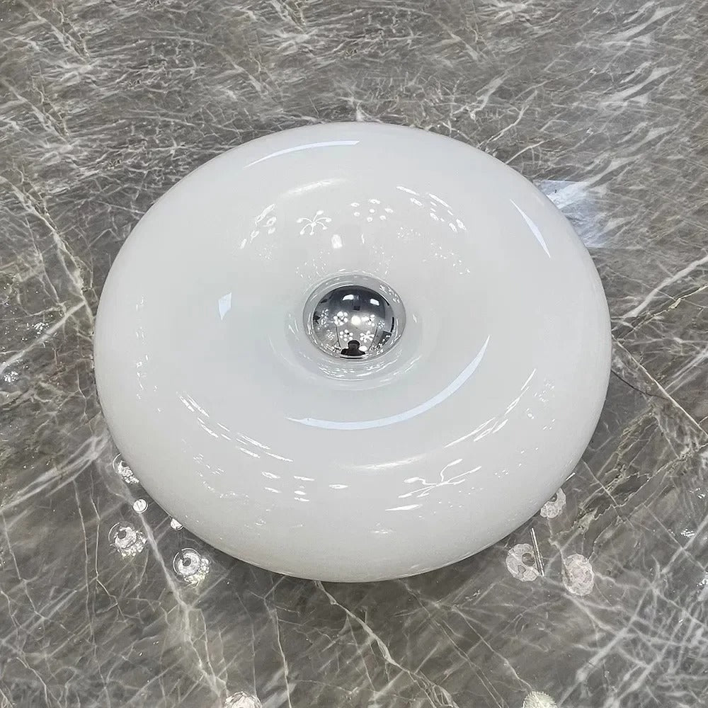 Orange donut-shaped LED lamp for table or wall, made of glass and metal, offering warm glow and whimsical décor touch.