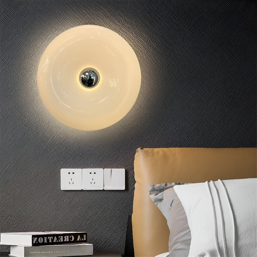Orange donut-shaped LED lamp for table or wall, made of glass and metal, offering warm glow and whimsical décor touch.