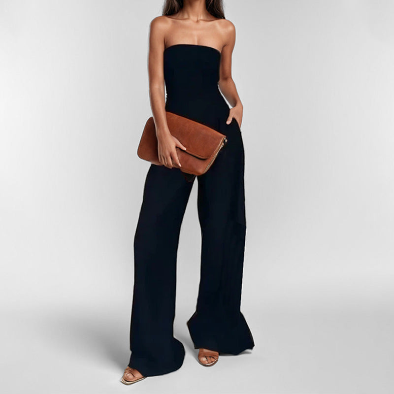 "Woman in strapless satin jumpsuit with tailored bodice, wide-leg cut, available in elegant colors like black and navy."