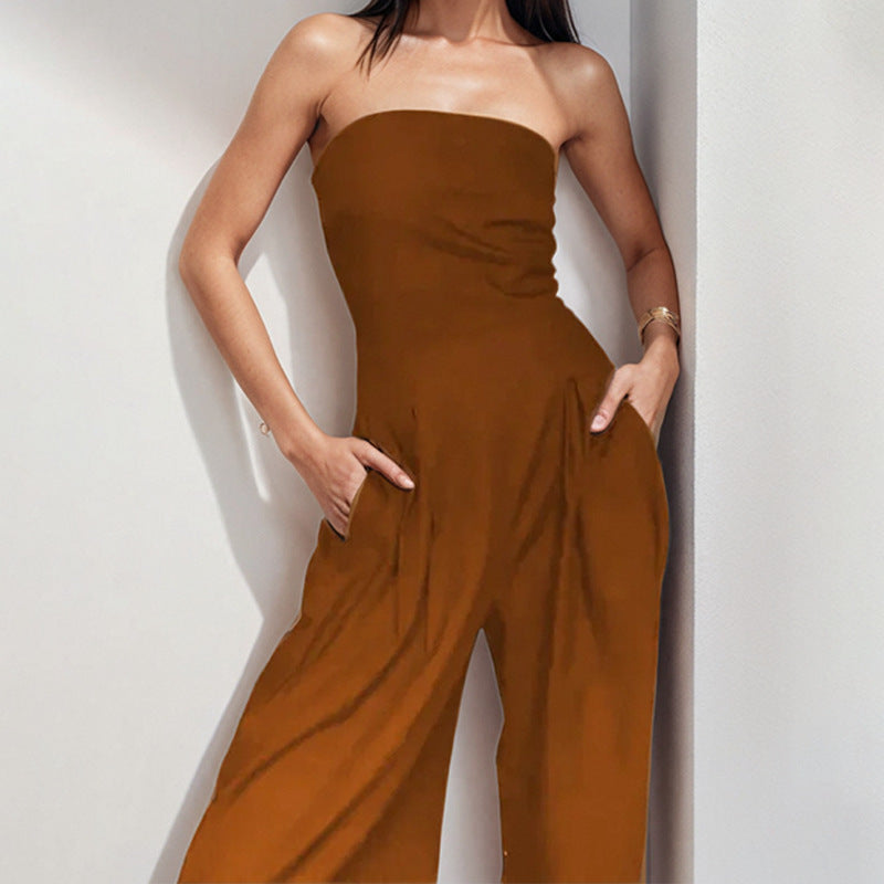 "Woman in strapless satin jumpsuit with tailored bodice, wide-leg cut, available in elegant colors like black and navy."