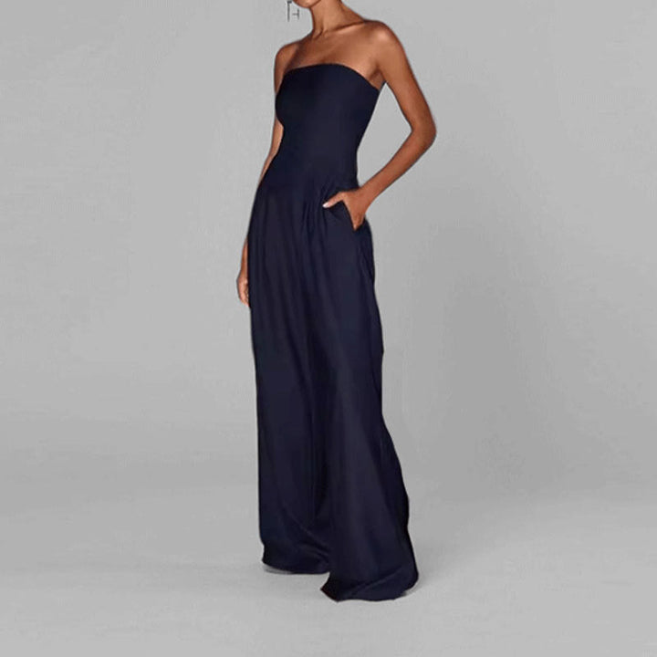 "Woman in strapless satin jumpsuit with tailored bodice, wide-leg cut, available in elegant colors like black and navy."