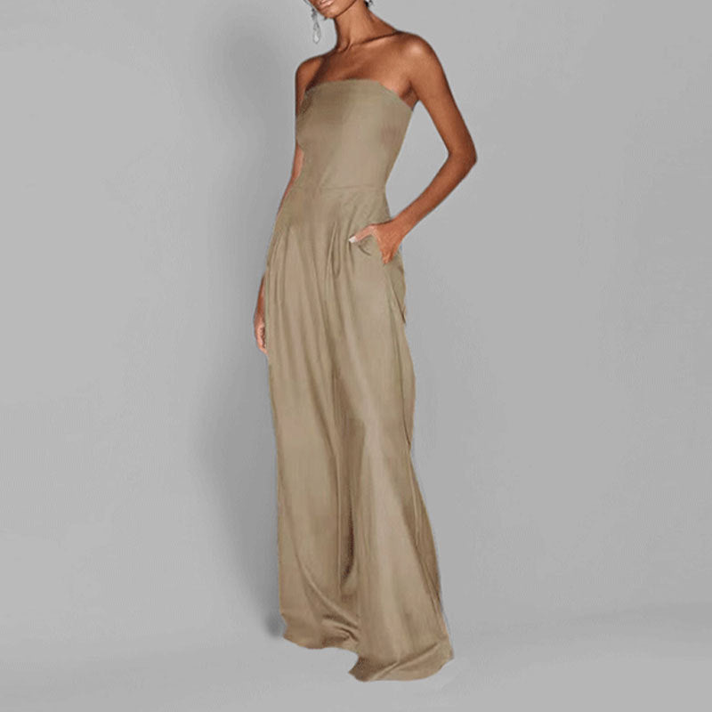 "Woman in strapless satin jumpsuit with tailored bodice, wide-leg cut, available in elegant colors like black and navy."